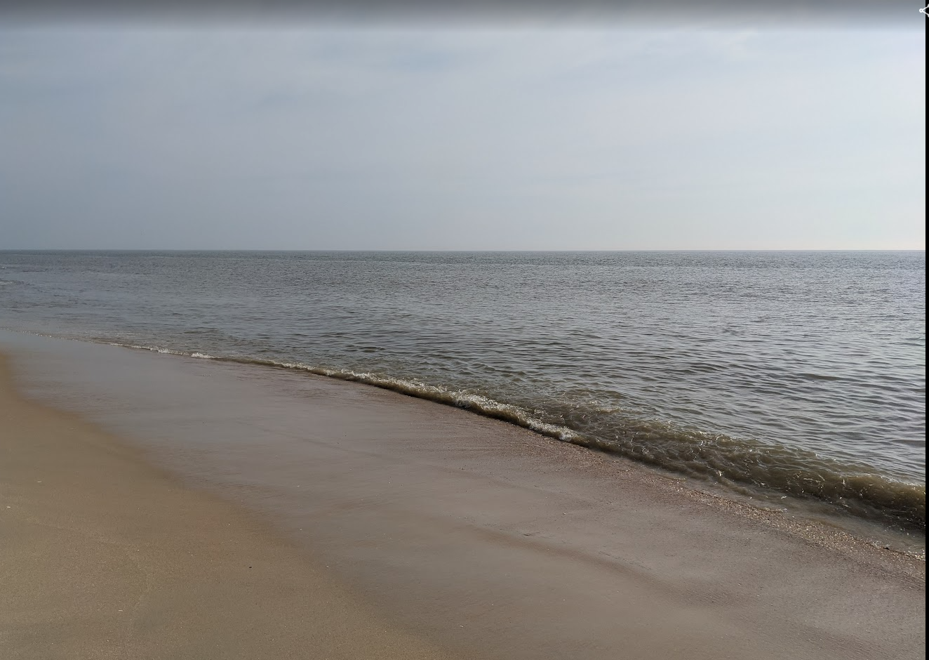 Gentle water meeting a quiet sandy shoreline on a Maryland or Delaware beach