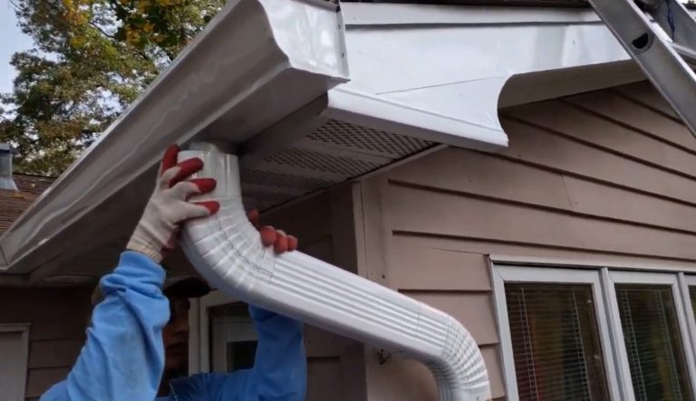 Next Day Gutters crew member installing a white downspout at a Columbia, Maryland home