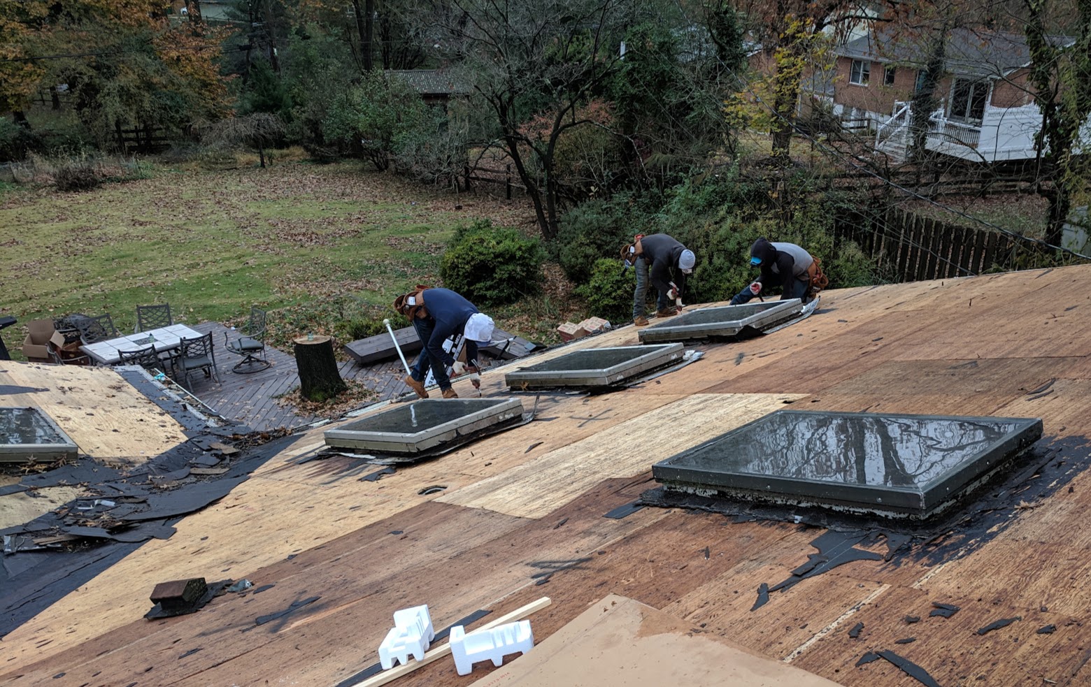 Roofing crew working around existing skylights during a roof replacement in Columbia, Maryland