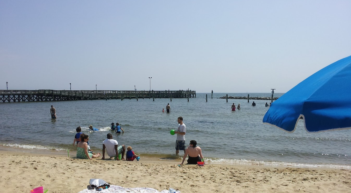 Families playing in the shallow Chesapeake Bay water at North Beach, Maryland with the fishing pier in the background
