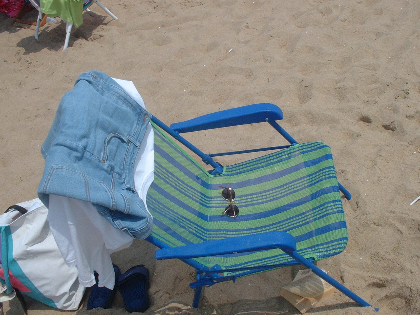 A folding beach chair, sandals, and bags on Ocean City sand